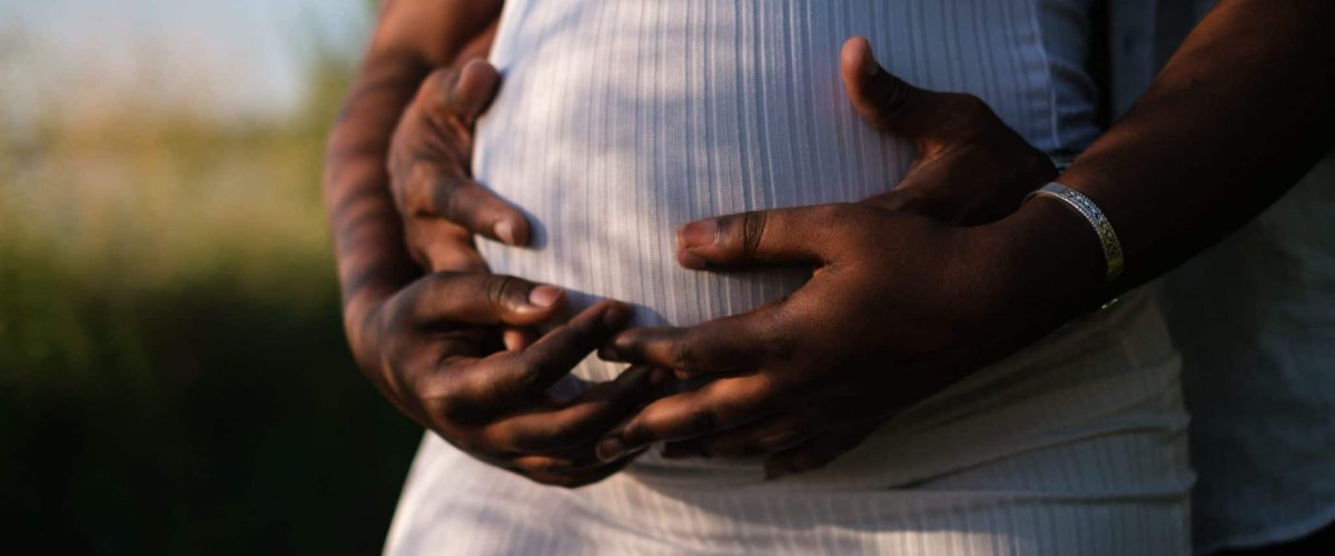 Hands of Man and Woman Cradling the Baby Bump